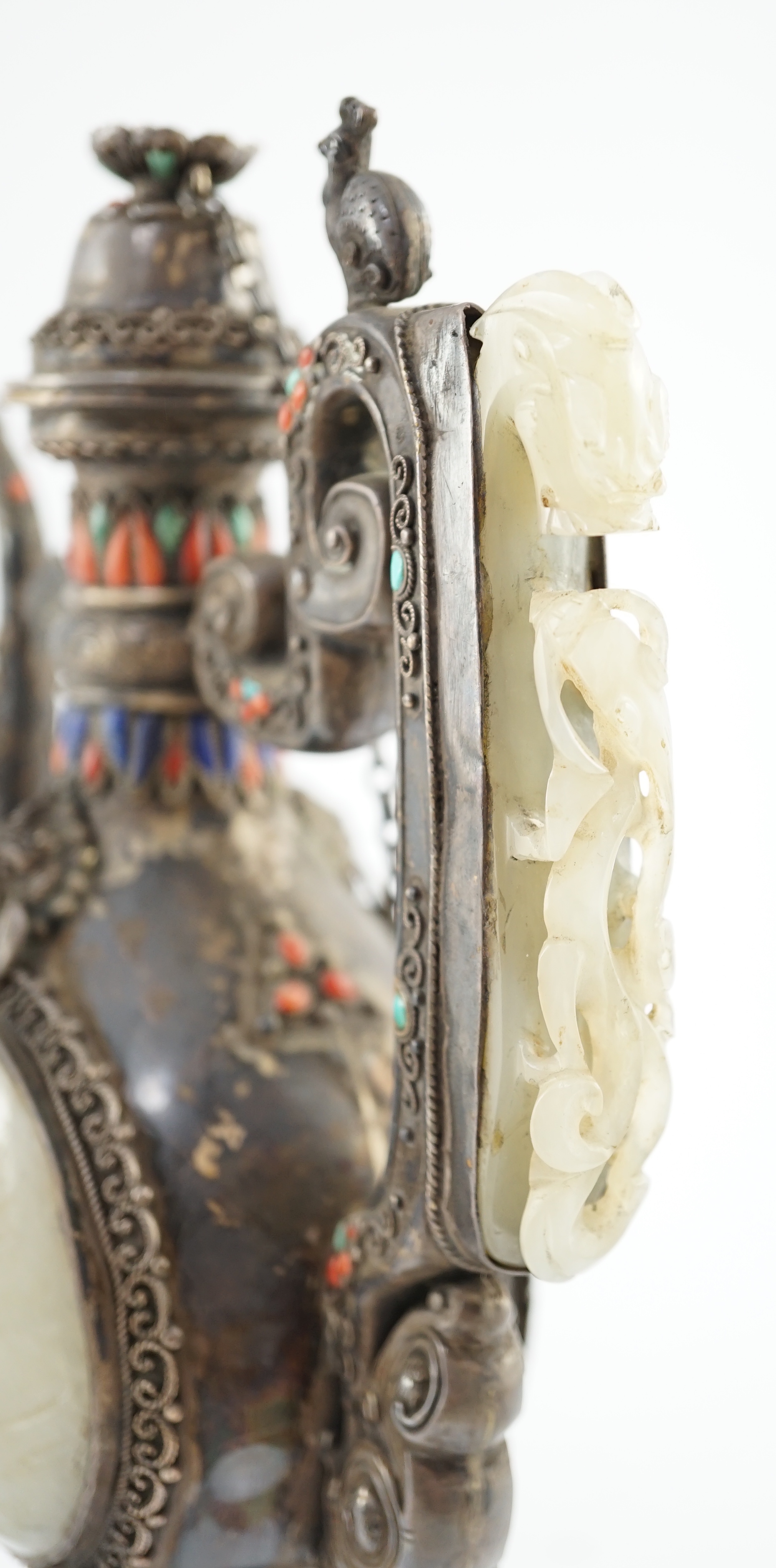 A Tibetan silver, jade, coral and hardstone mounted ewer, late 19th century, the Chinese pale celadon jades, 18th/19th century finial lacking stones